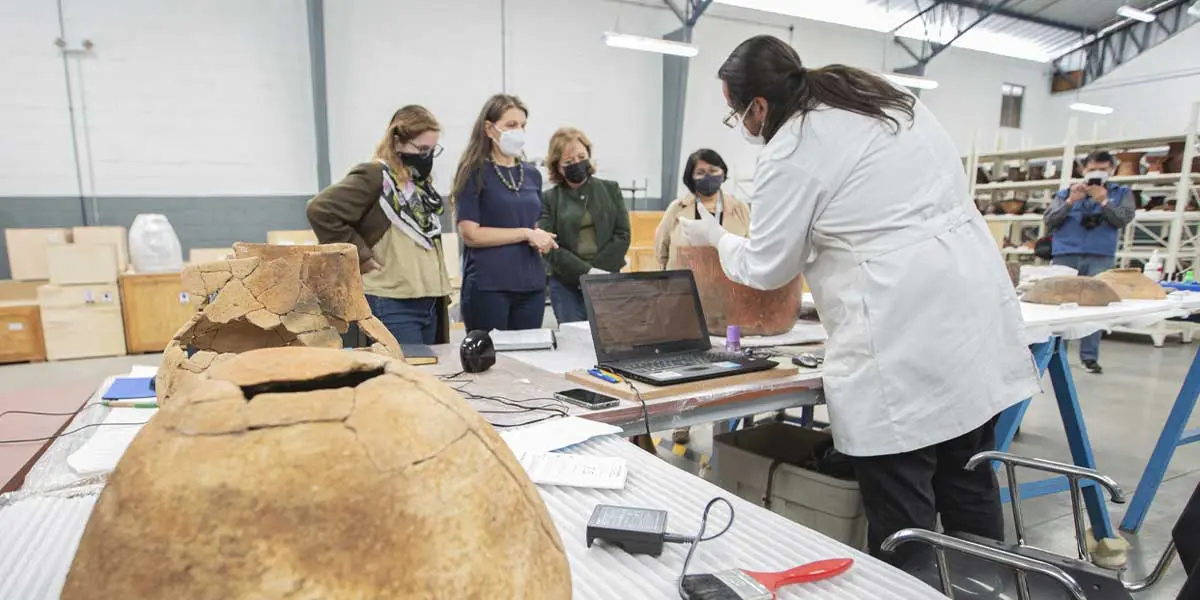 museum job worker showcasing an ancient clay pot to 4 women