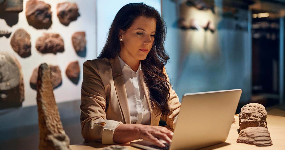 A museum curator working on a laptop to digitize an exhibit.