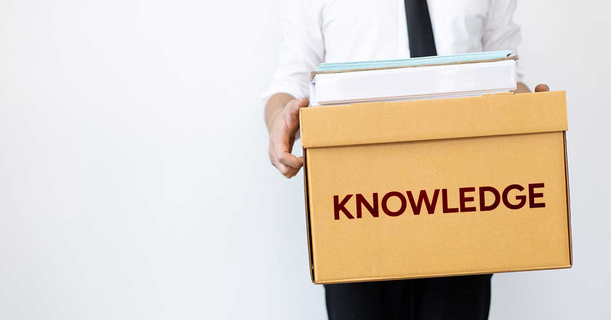 A person holding a cardboard box labelled Knowledge