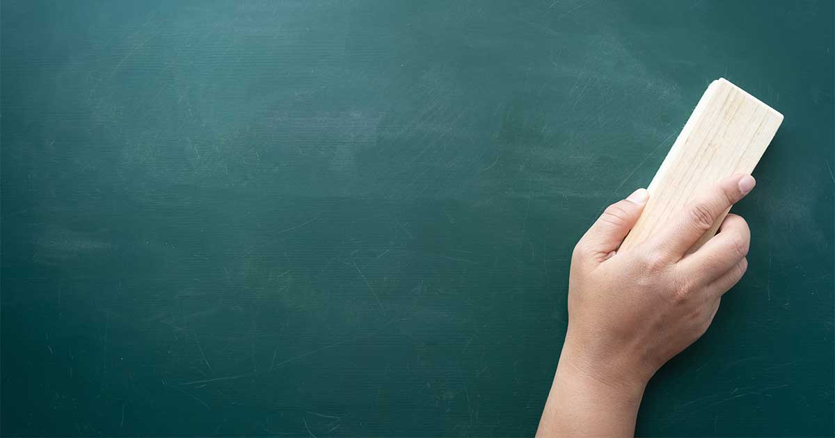 A hand swiping an eraser over a chalkboard