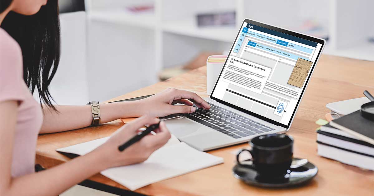 The cover image for The Architecture of Partnership: Record Forms for Cross-Searchable Data blog post by Rachael Cristine Woody, showing a woman writes in a notebook while using a laptop at a desk. The screen displays the back-end of an Argus Museum CMS portal. Nearby, a cup of coffee and books create a productive atmosphere.