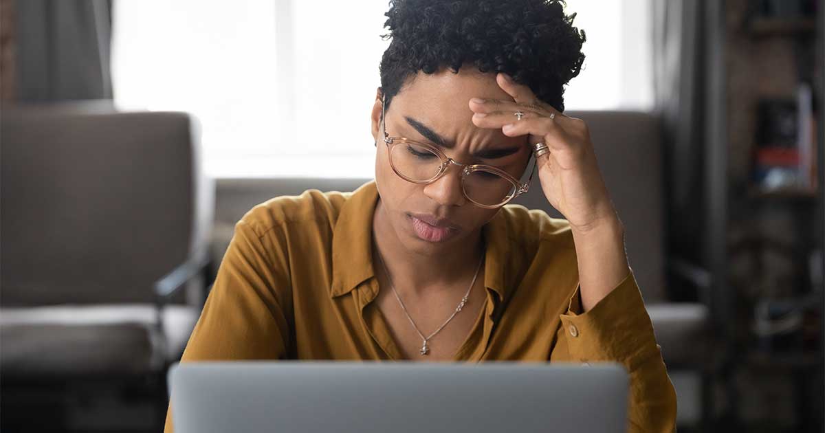 A person with a furrowed brow looking at their computer.