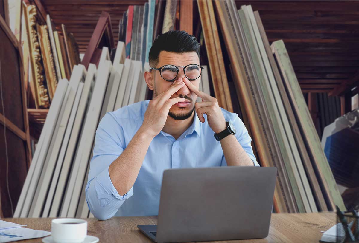 A museum worker rubbing his eyes in front of a laptop.