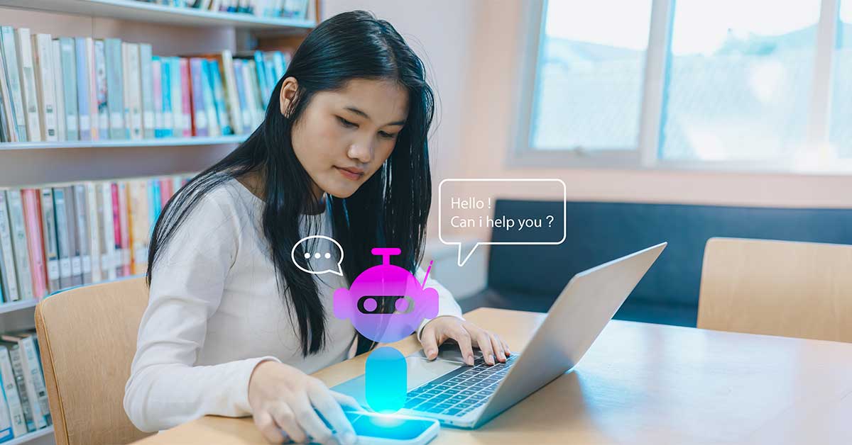 A person sitting at an library desk with a robot and chat bubble appearing above her mobile device.