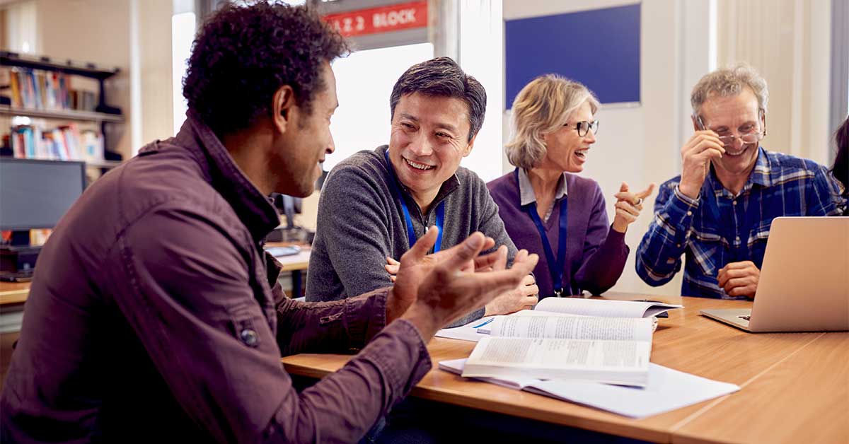 A group of colleagues talking at a table, representing knowledge sharing.