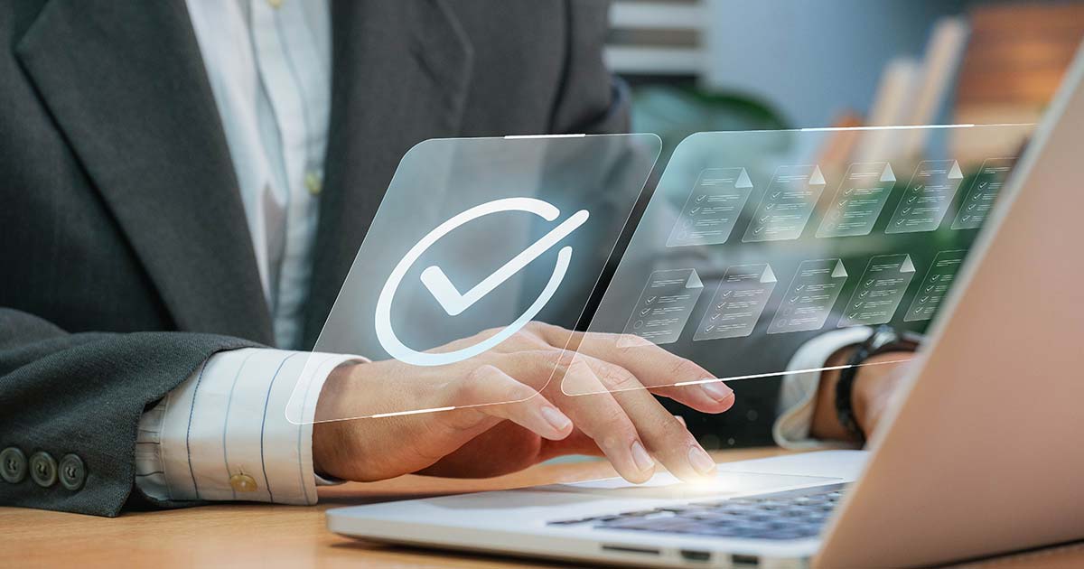 A person working on their laptop with a checkmark graphic floating above the keyboard