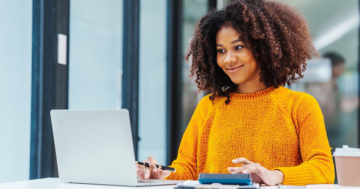 A knowledge management professional with a laptop and calculator on her desk.