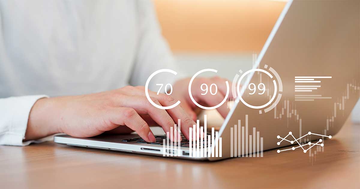 Hands type on a laptop with transparent dashboard graphics overlaid, including scores of 70, 90, and 99 and bar charts.
